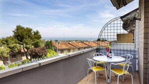 A balcony with a table and chairs, overlooking a residential area with houses and trees.