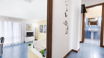 Una camera d'albergo moderna con un letto, una televisione, una scrivania e una finestra con tende.