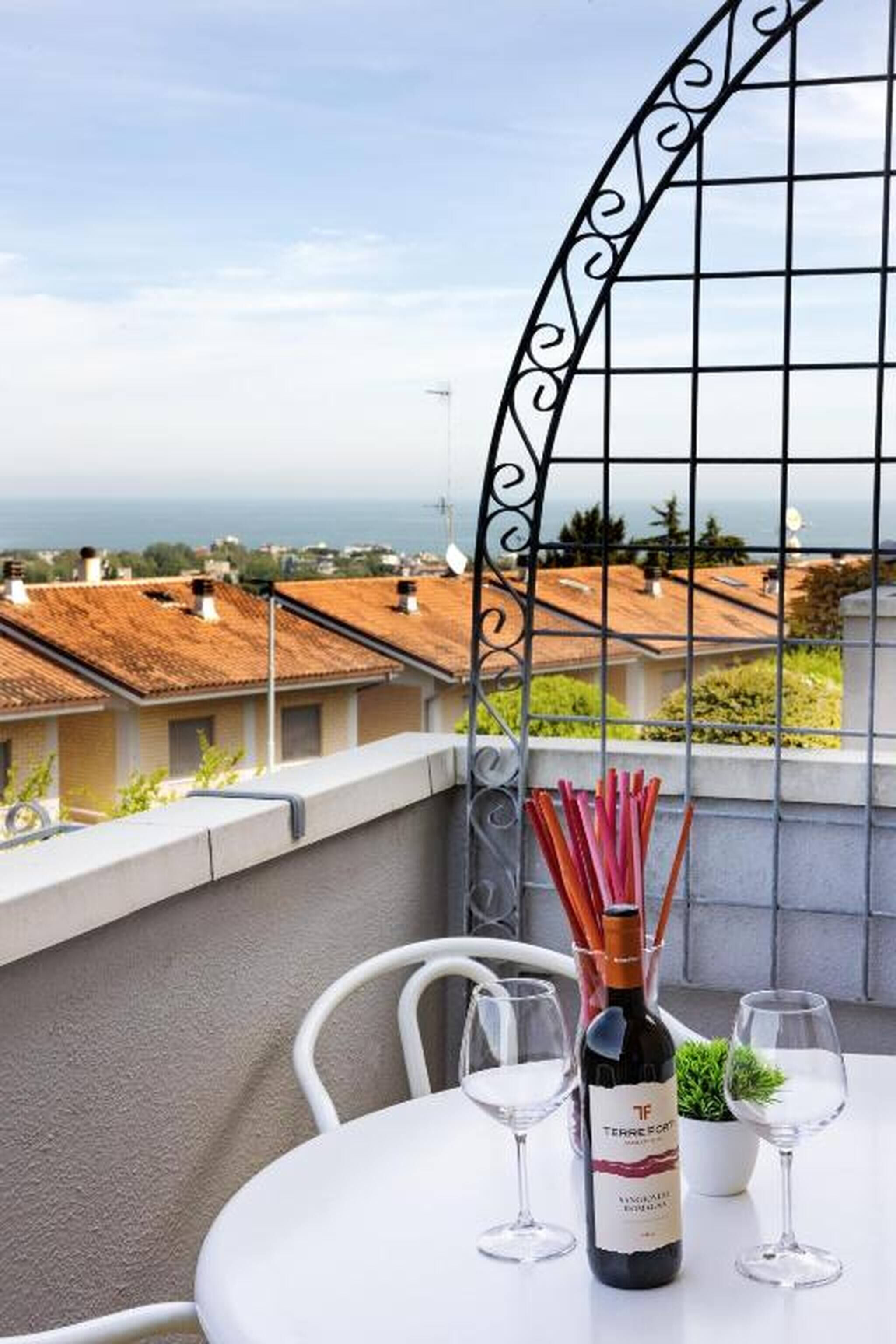 Ein Balkon mit einem Tisch für zwei Personen, einer Weinflasche und einem Glas.