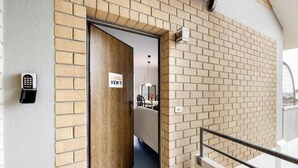 Een hotelingang met een bakstenen muur, een houten deur en een bord waarop 'CASOLI VIEW 11' staat.
