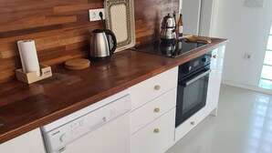 Uma cozinha moderna com armários brancos, bancada de madeira, forno embutido e máquina de café.