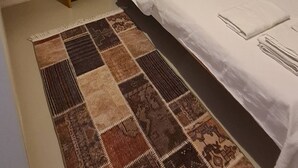 Um quarto com uma cama de solteiro, uma mesa de cabeceira, um abajur e um tapete estampado.
