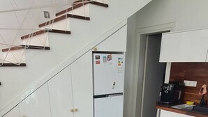Uma cozinha moderna com armários brancos, geladeira embutida e um espaço de refeições com mesa e cadeiras.