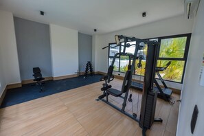 A gym with exercise equipment, a bench, and a large window with a view. - Modern Apartment with Private Pool in Punta Cana (Punta Cana)