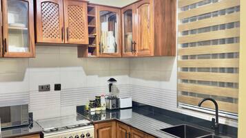 A kitchen with wooden cabinets, a stove, a microwave, and a sink.