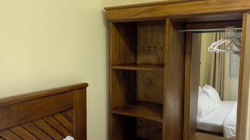 Une chambre d’hôtel avec une tête de lit en bois, un grand miroir et une armoire dotée de plusieurs étagères et d’un espace pour suspendre les vêtements.