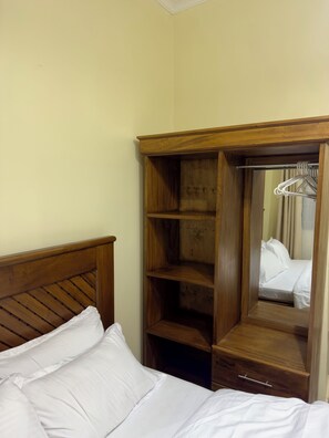 A hotel room with a wooden headboard, a large mirror, and a wardrobe with multiple shelves and hanging space. - Aiden House Arusha: 2BR Apartment, Free Parking/WiFi, Close to Arusha Centre (Arusha)