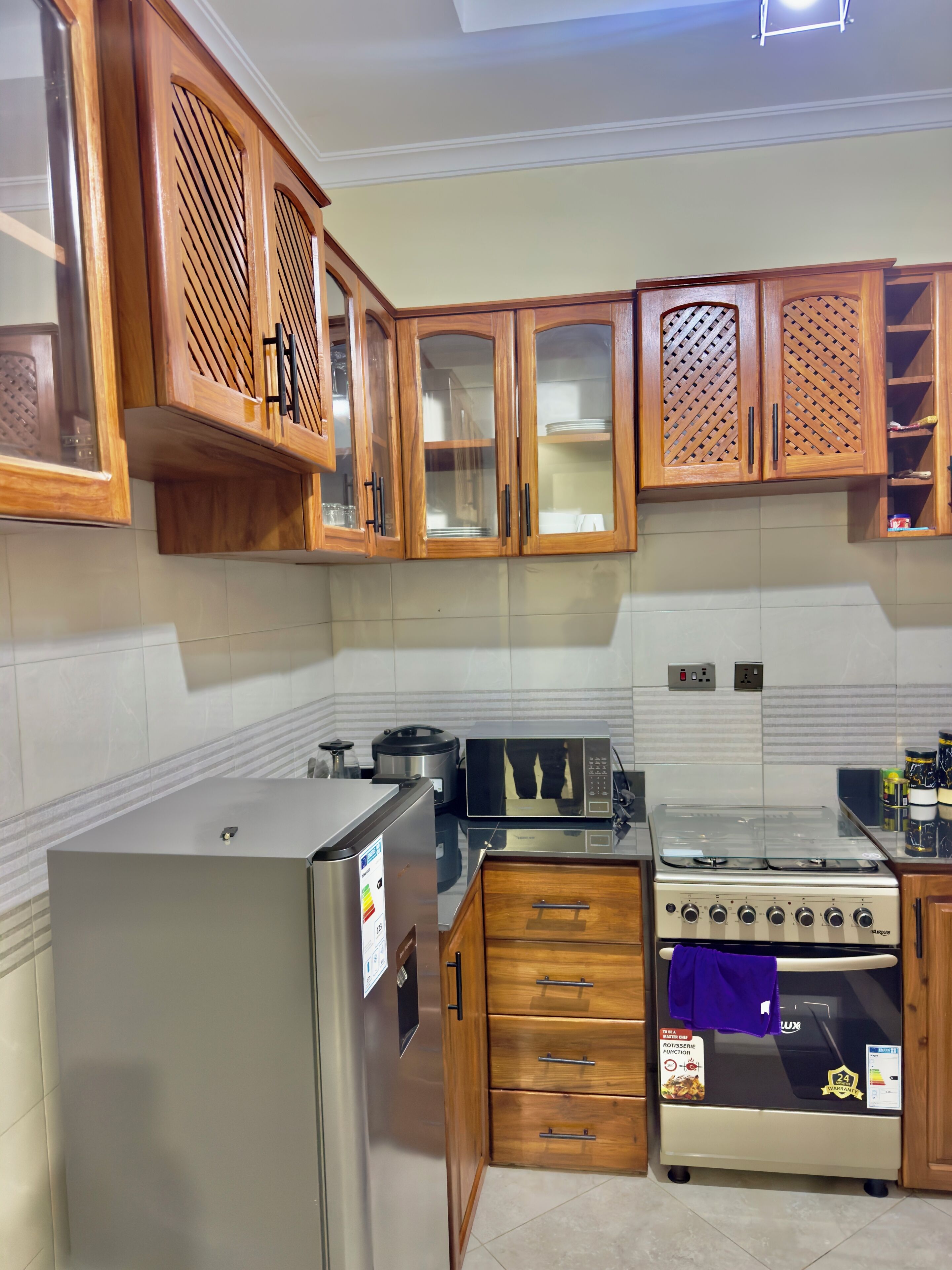 A kitchen with wooden cabinets, a stainless steel refrigerator, a microwave, a stove, and a dishwasher.