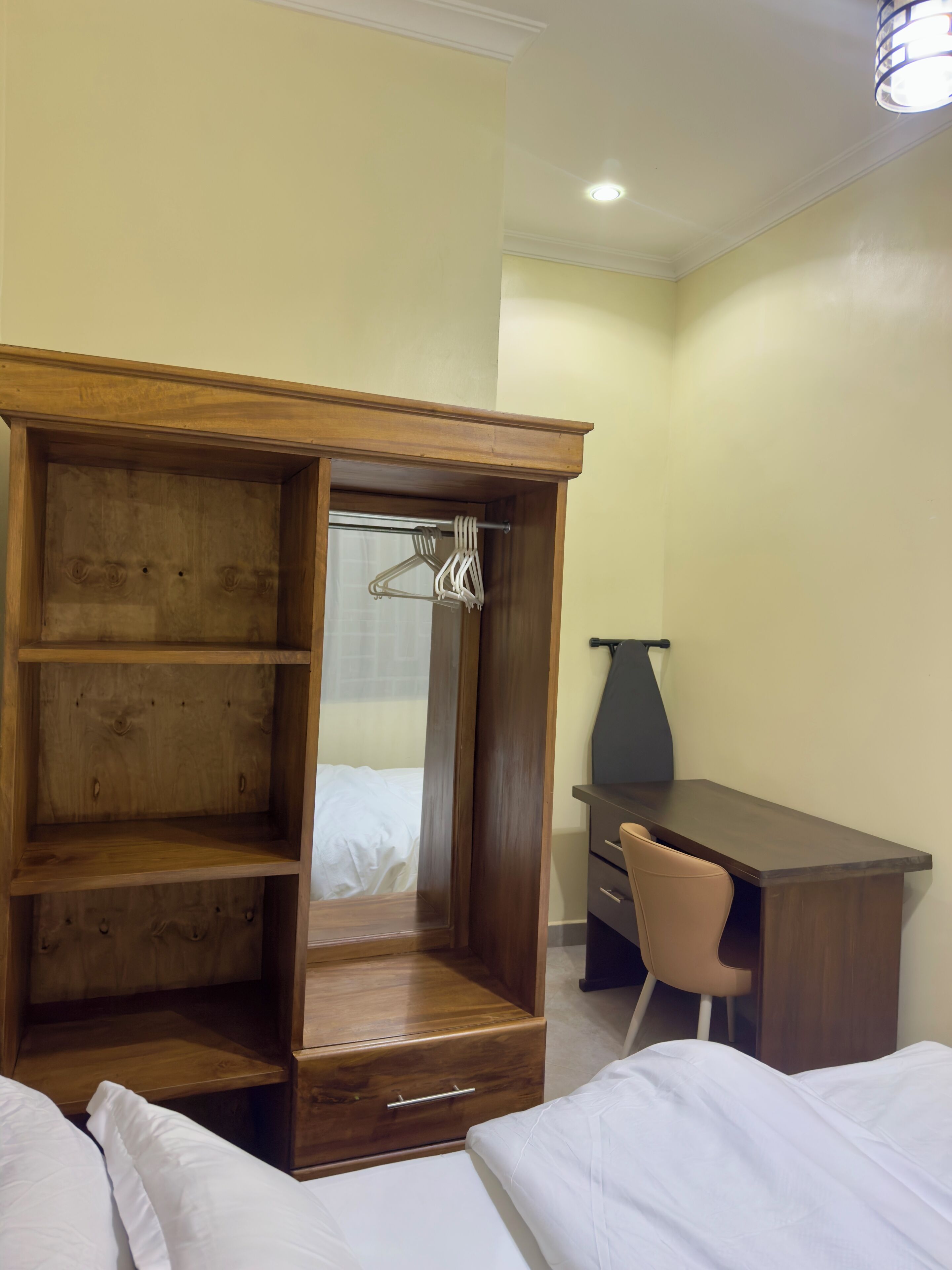 Une chambre d’hôtel avec une armoire en bois, un bureau, une chaise et un lit.