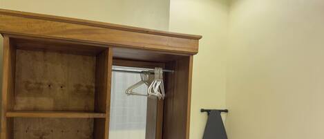 A hotel room with a wooden wardrobe, a desk, a chair, and a bed.