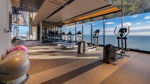 Ein Fitnessstudio mit Laufbändern, Crosstrainern und Reebok-Trainingsbällen, das einen schönen Ausblick bietet.