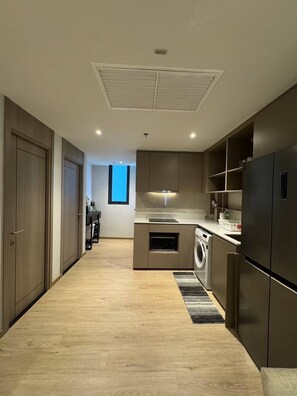 Uma cozinha moderna com máquina de lavar e secar integradas, soalho em madeira e vista para o exterior.