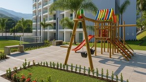 Un terrain de jeux équipé d’un toboggan et d’une structure d’escalade, entouré d’un jardin bien entretenu et d’un court de tennis.