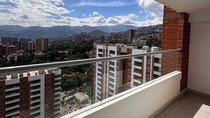 Ein Balkon mit Blick auf eine Stadtlandschaft, einschließlich Wolkenkratzern und Bergen.