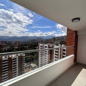 A balcony with a view of a cityscape, including high-rise buildings and mountains. - Epic View 25 • Pablo Tobón Cardiovascular • (Medellín)