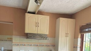 A kitchen with beige cabinets, a stove, oven, and a window with a view. - VM Guesthouse Hazyview Mpumalanga South Africa (Hazyview)