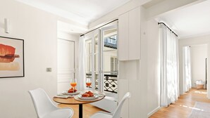 Comedor con una mesa preparada para dos, una ventana con cortinas y vistas a un balcón.