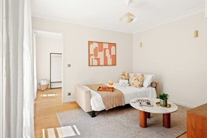 A modern bedroom with a bed, bedside table, and a wall-mounted abstract painting. - Chic 2BR in the Heart of Paris 2 (Paris)