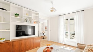Una sala moderna con televisor, aparador de madera y comedor con mesa y sillas.