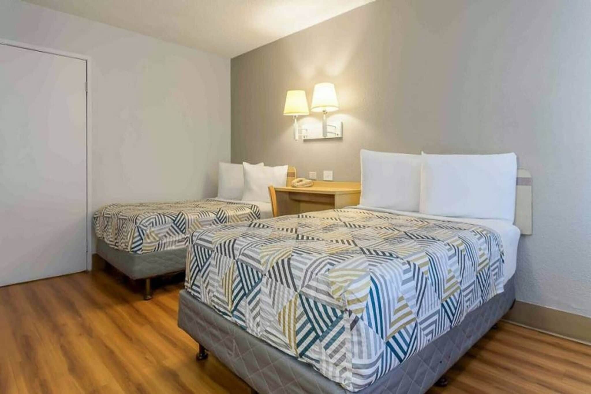 A hotel room with two beds, a desk, and a chair.