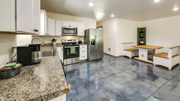 A modern kitchen with white cabinets, stainless steel appliances, granite countertops, and a built-in bench seating area. - Bring Your Boat! Updated Cabin in Priest River (Priest River)