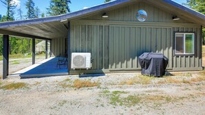 A single-story building with a covered porch, an air conditioning unit, and a barbecue grill. - Bring Your Boat! Updated Cabin in Priest River (Priest River)