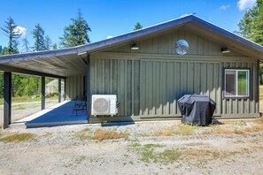 A single-story building with a covered porch, an air conditioning unit, and a barbecue grill.