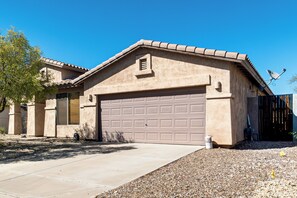 A residential building with a garage, a satellite dish, and a clear blue sky. - 5 Mi to Estrella Mtn Park! Home w/ Outdoor Oasis (Goodyear)