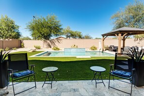 A backyard with a swimming pool, artificial grass, and outdoor furniture. - 5 Mi to Estrella Mtn Park! Home w/ Outdoor Oasis (Goodyear)