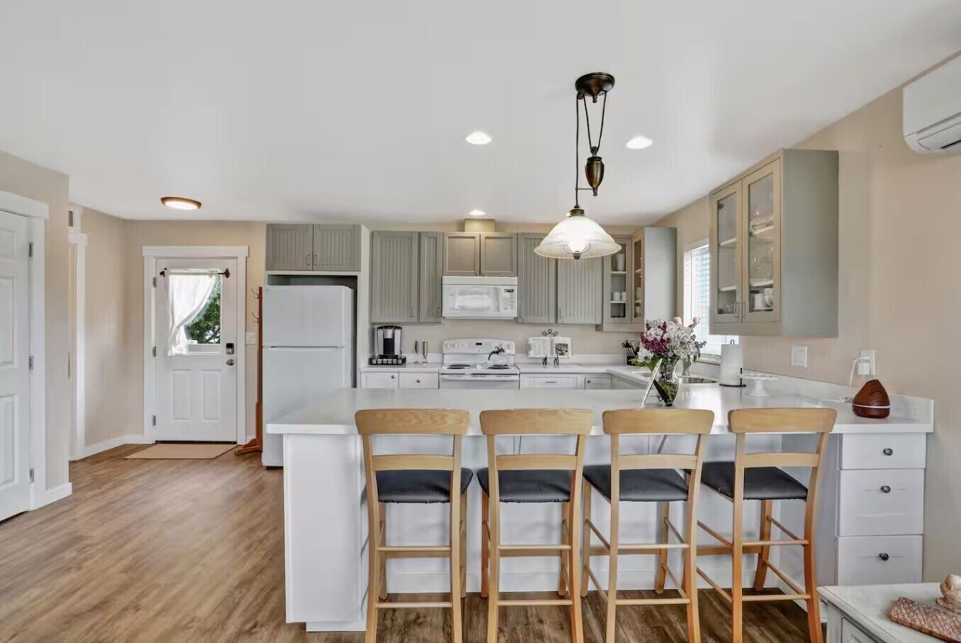 A modern kitchen with a central island, white cabinetry, and a hanging light fixture.