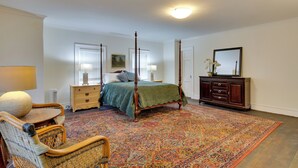 Een slaapkamer met een hemelbed, een kaptafel, een stoel en een groot vloerkleed.