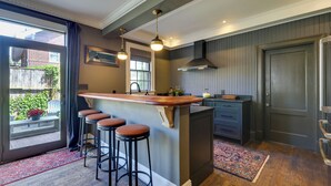 Een keuken met een bar, houten krukken, een raam met gordijnen, een deur en een kamerbreed tapijt.
