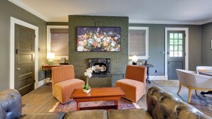 Een woonkamer met een open haard, twee fauteuils, een bank en een salontafel.
