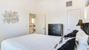 Una camera da letto con un letto, una cassettiera, un'opera d'arte a parete e una porta.