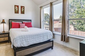 A bedroom with a bed, a nightstand, a lamp, and a window with curtains. - Arlington Home w/ Pool: Just Over 1 Mi to Stadium (Arlington)