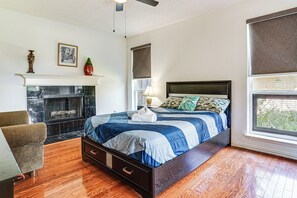 Ein Schlafzimmer mit einem Bett, einem Sessel, einem Kamin und einem Fenster.