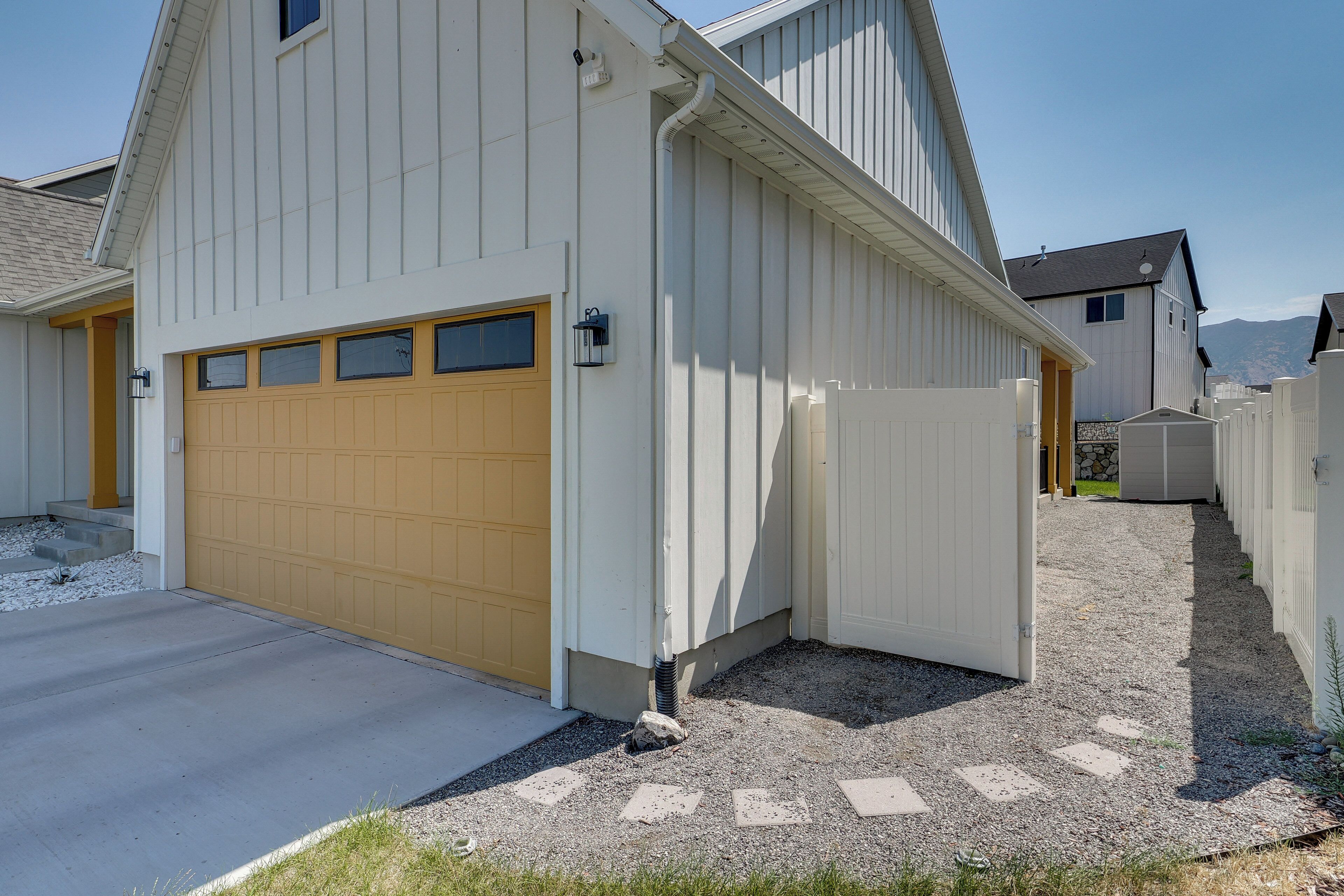 A residential building with a garage, a covered driveway, and a gravel pathway leading to the entrance.