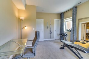 A home gym with exercise equipment, a glass table, and a door.
