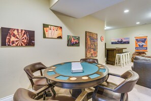 A room with a dartboard, playing cards, and a Denver Broncos banner.