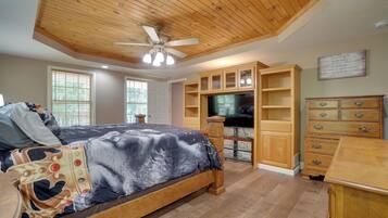 A bedroom with a bed, wooden ceiling, built-in TV, and wooden furniture.