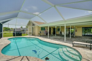 Una piscina techada al aire libre con un patio, sillas y césped.
