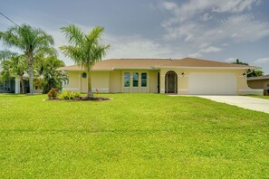A single-story house with a flat roof, a front door, and a garage. - On Preserved Land w/ Pool & Trails! Cape Coral Gem (Cape Coral)