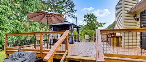 A wooden deck with a covered grill, outdoor seating, and a gazebo.