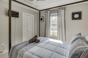 Ein Schlafzimmer mit Bett, einem fenster mit Vorhängen, einem Deckenventilator und einem Wandbild.