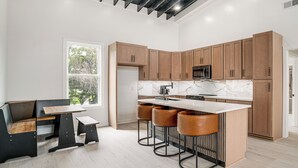 A modern kitchen with wooden cabinets, a marble countertop, and a bar area with stools. - Close to Ohio River: 6BR Jeffersonville Home (Jeffersonville)