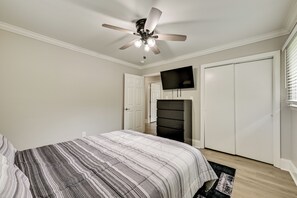 A bedroom with a bed, a ceiling fan, a TV mounted on the wall, and a wardrobe. - Lake Norman Launchpad: Home Near Dtwn Mooresville (Mooresville)