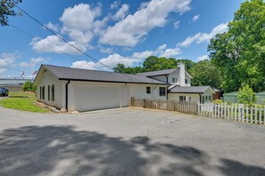 A single-story building with a garage, a fenced yard, and a clear sky. - Lake Norman Launchpad: Home Near Dtwn Mooresville (Mooresville)