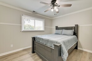Ein Schlafzimmer mit einem Bett, einem Deckenventilator, einem Fenster und einem Lichtschalter an der Wand.