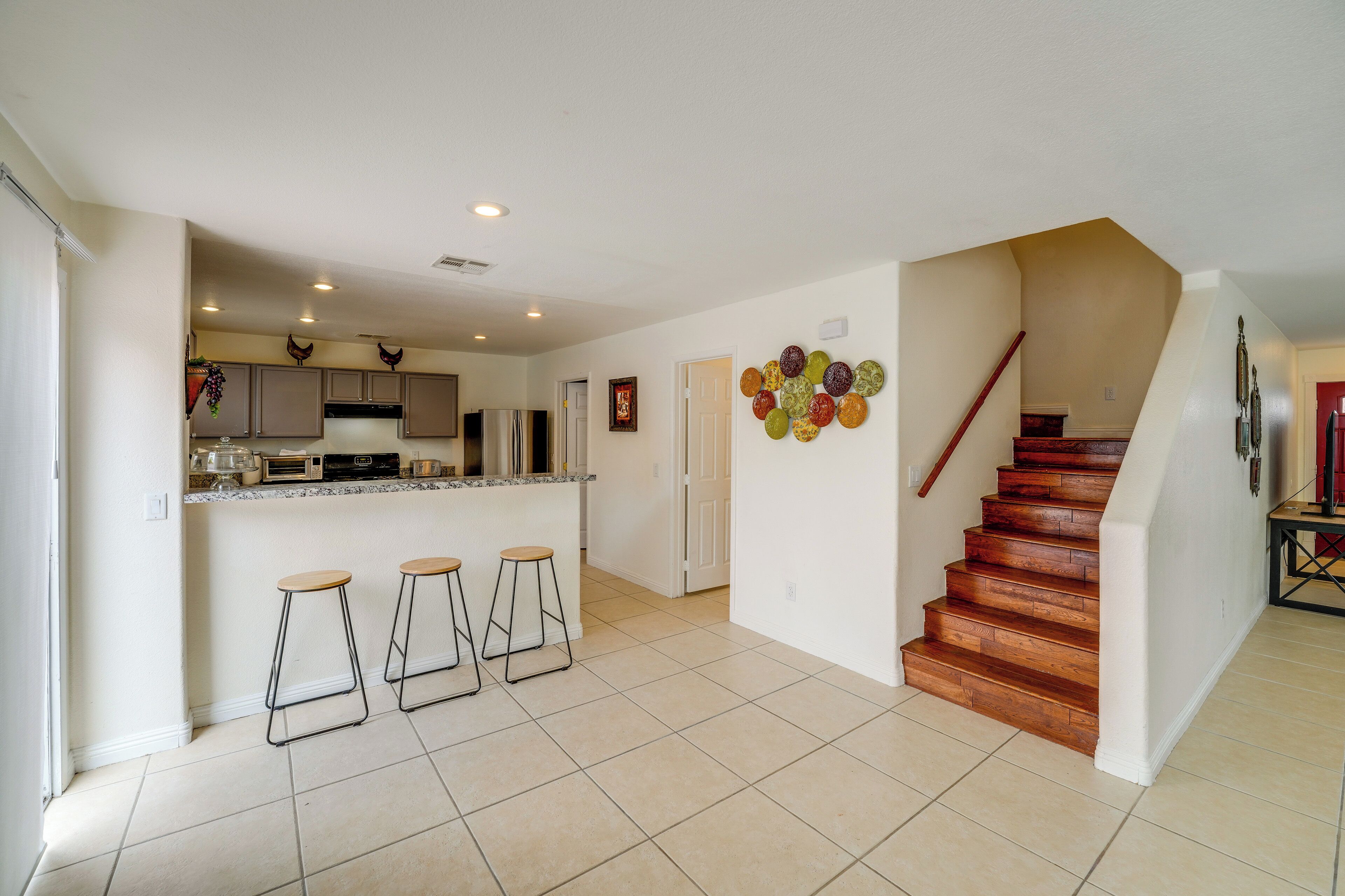 A spacious kitchen with a central island, bar stools, and a staircase leading to a lower level.