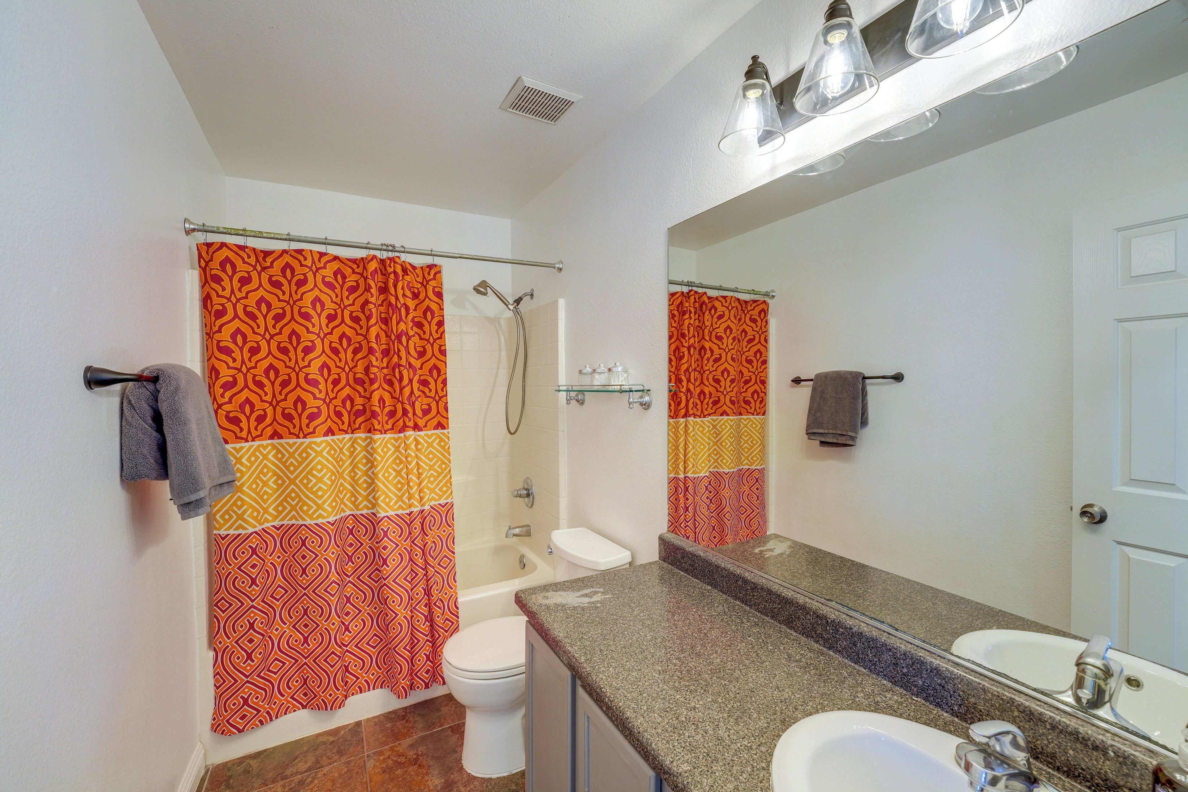 Un baño con ducha, inodoro, lavamanos y un espejo grande.
